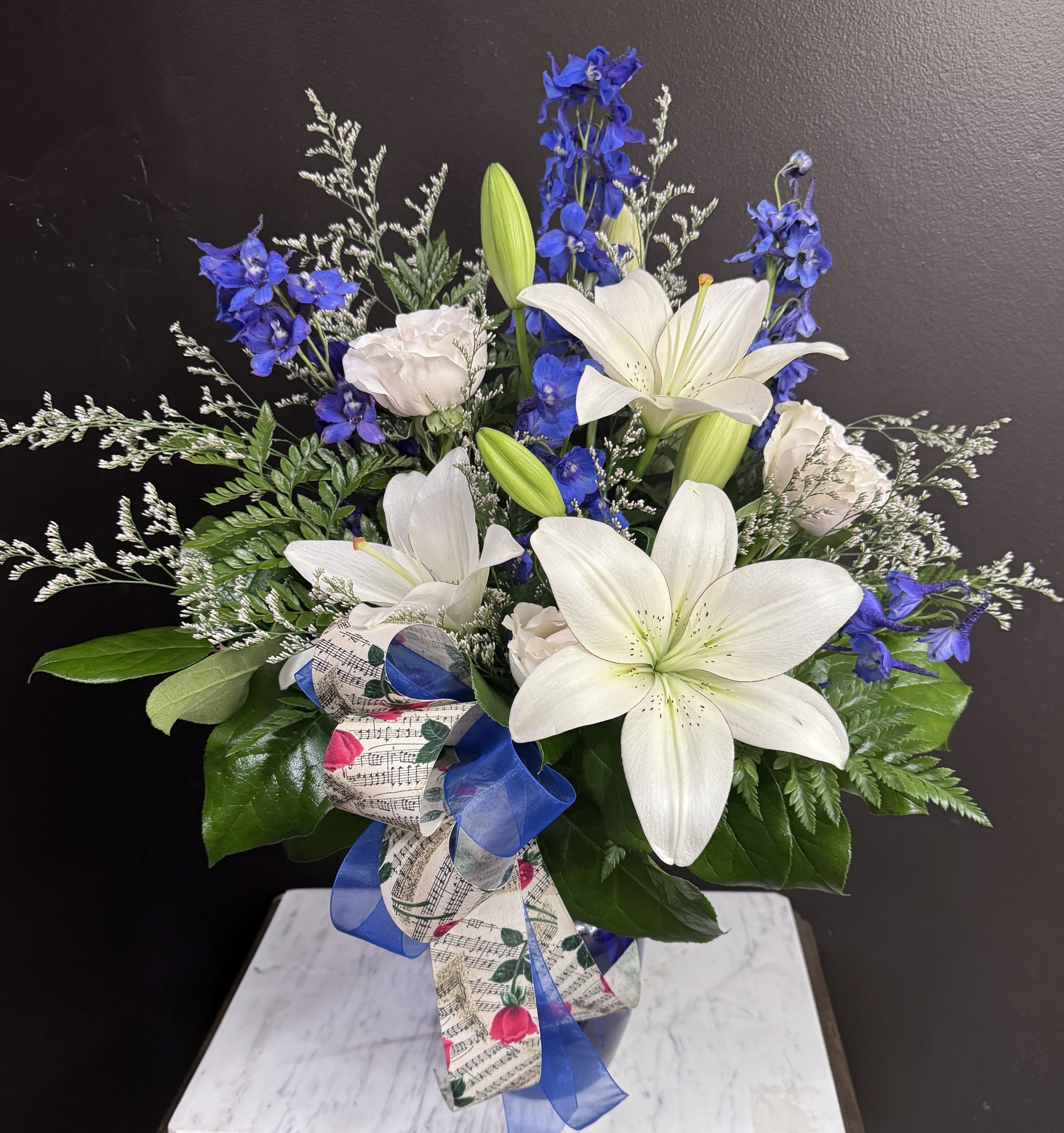 Play The Blues - Blue and white flowers in a clear vase with sheet music ribbon, for your special music lover.