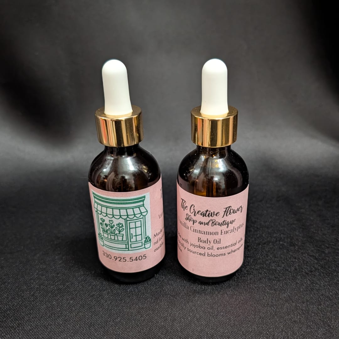 Two dropper bottles of body oil with pink labels on a dark background