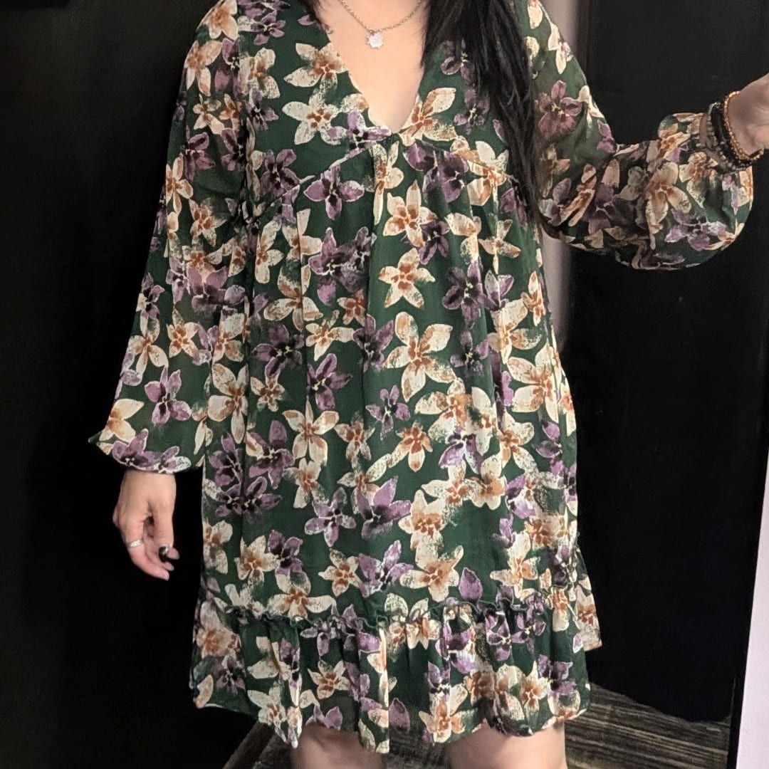 Woman wearing a dark green floral dress with long sleeves