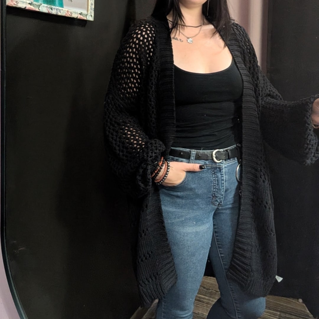 Woman wearing a black cardigan, black top, and blue jeans