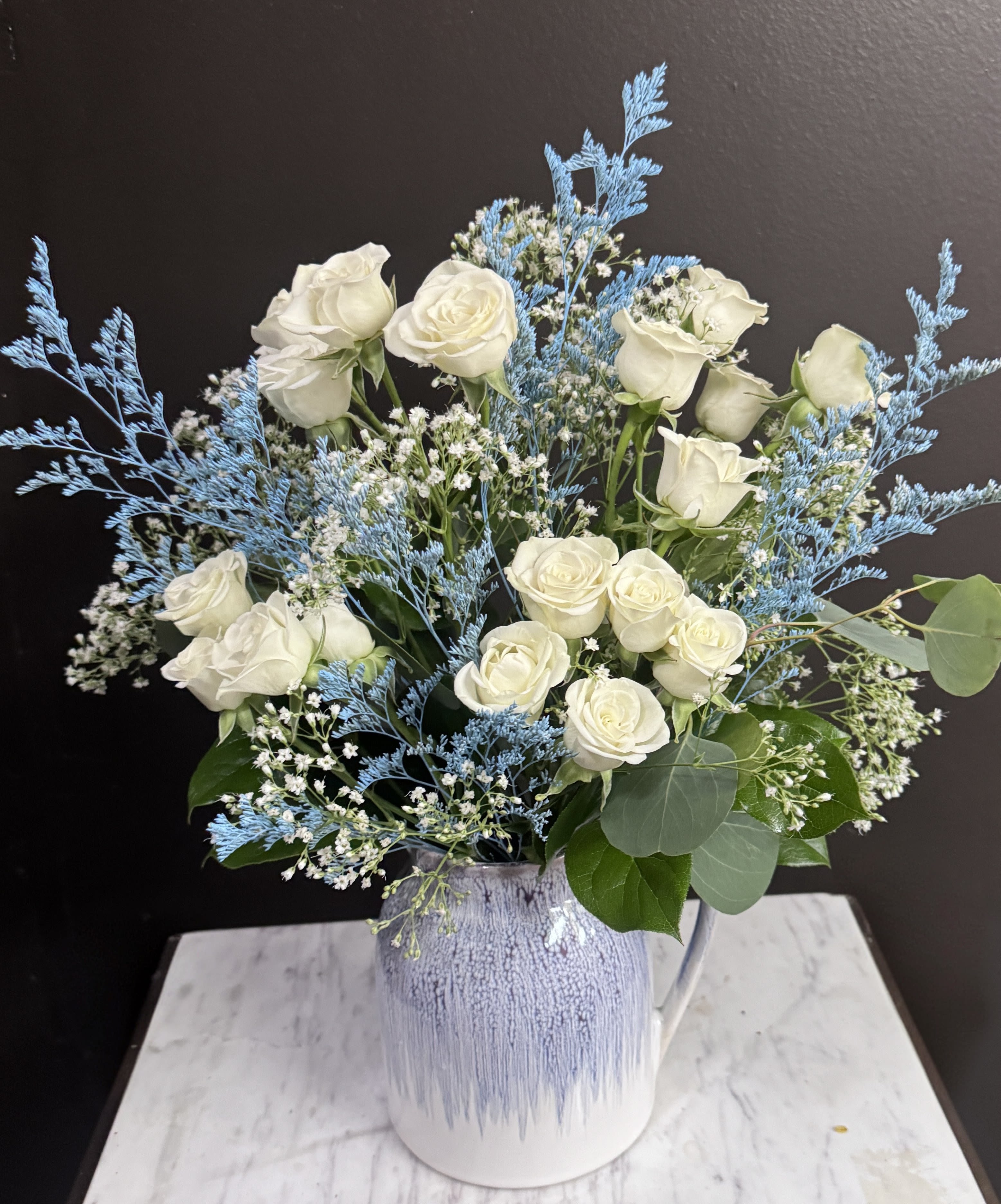 White roses in a blue-and-white ceramic vase with airy blue filler