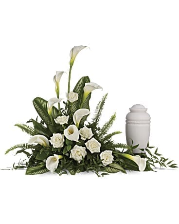 White calla lilies and roses arranged beside a white urn