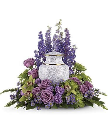 Purple floral arrangement around a white urn-shaped vase