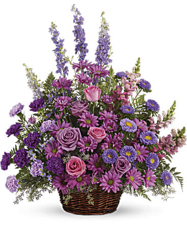 Purple and pink mixed flower arrangement in a wicker basket
