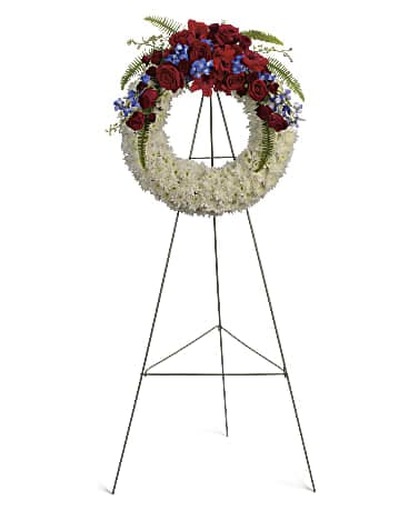 Standing funeral wreath with red and white flowers and blue accents on an easel