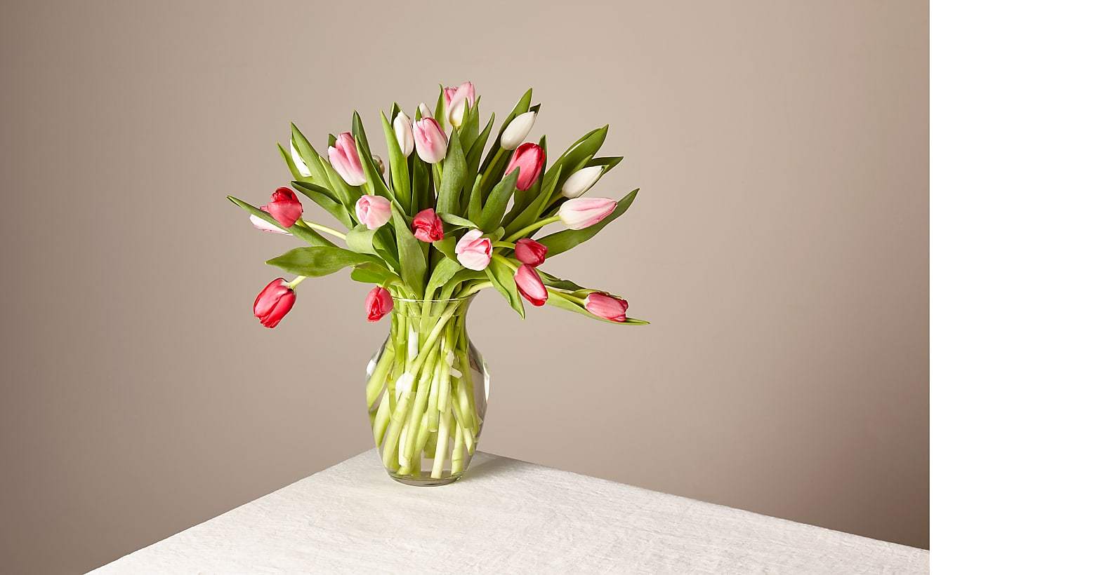 Bouquet of pink and white tulips in a clear glass vase