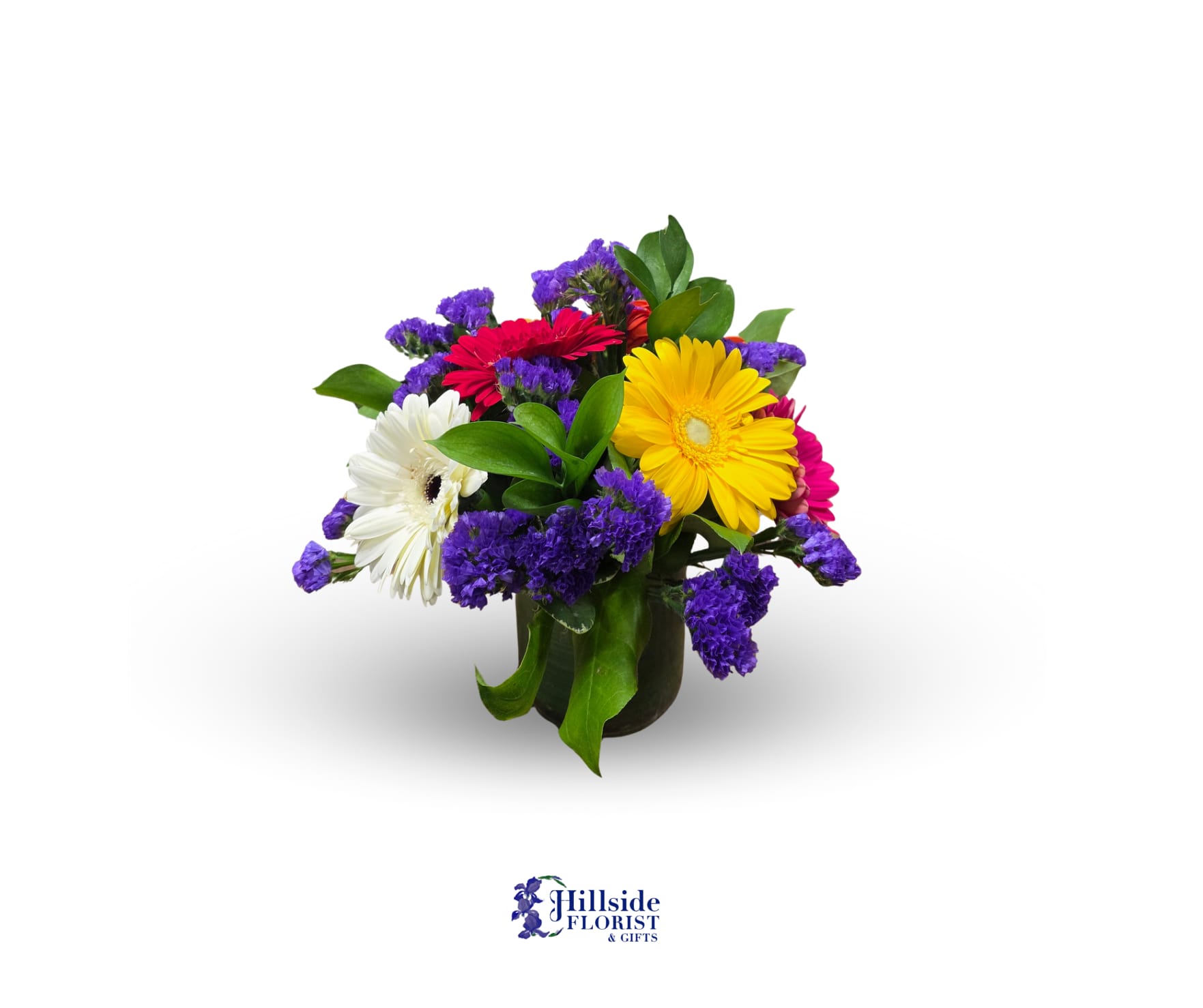 Short bouquet of yellow, red, pink, and white gerbera daisies with purple filler in a glass vase