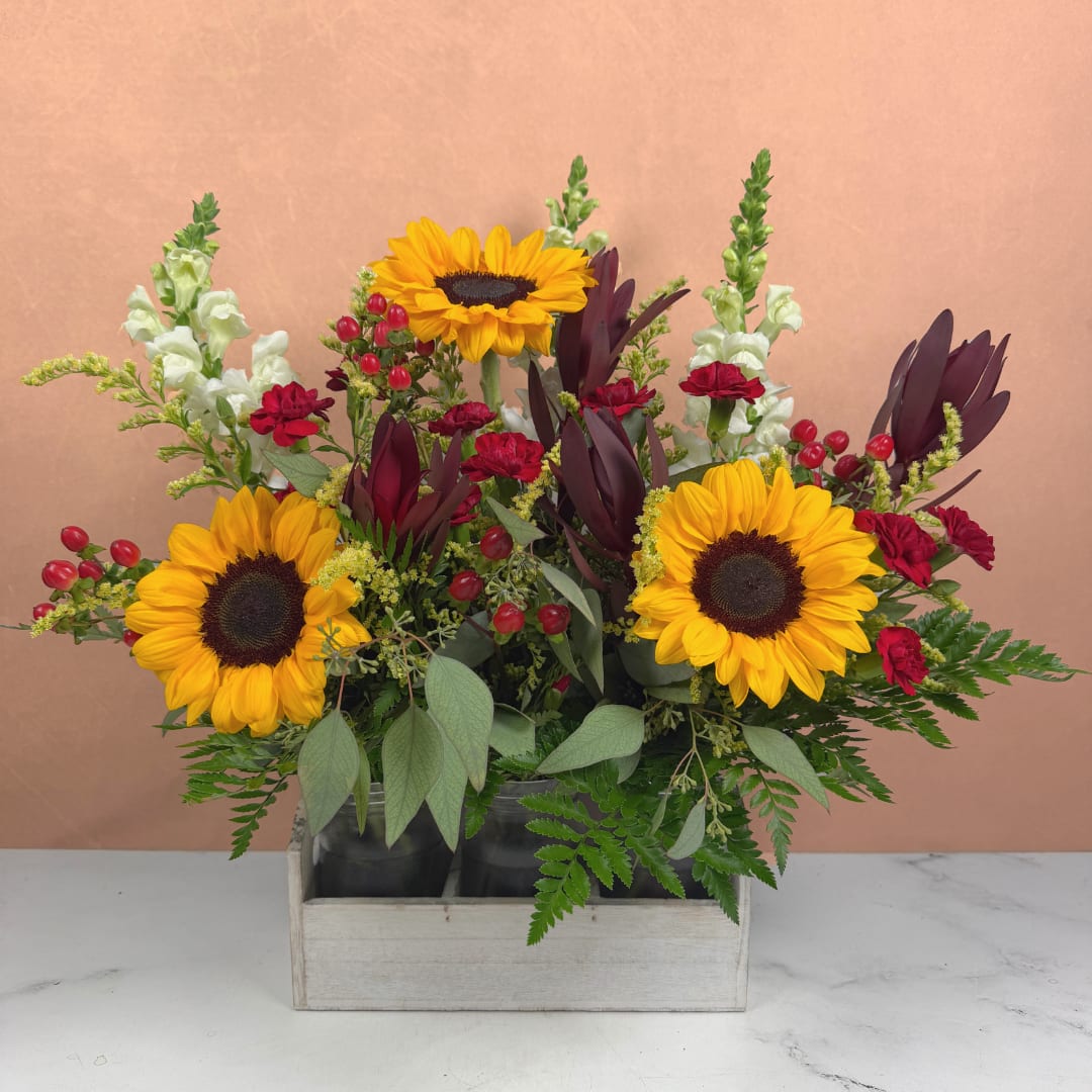 Sunflowers and red carnations arranged in a wooden box