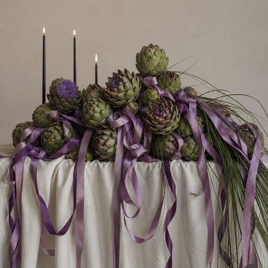 Artichoke centerpiece with purple ribbons and tall black candles