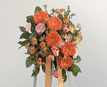 Orange and pink floral standing arrangement with ribbon streamers