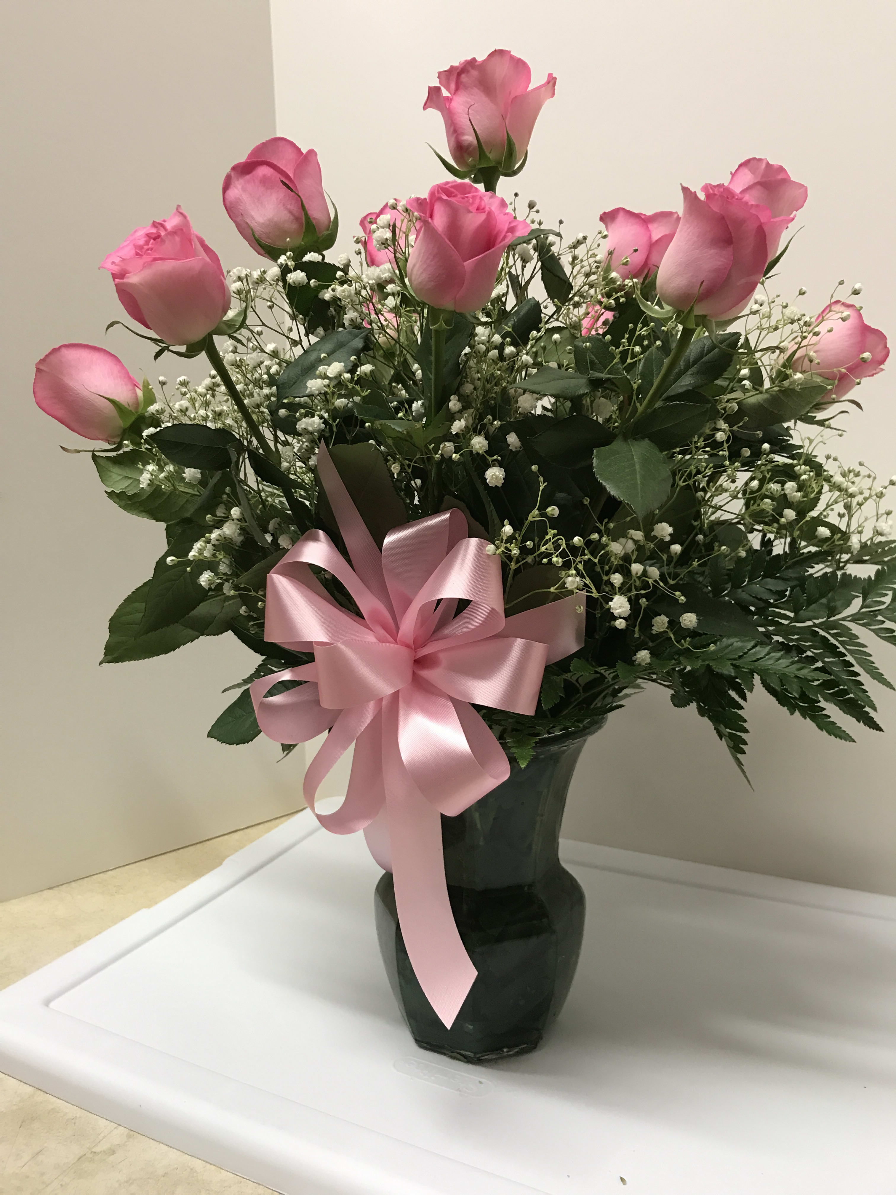 Pink roses in a dark vase with a pink ribbon bow
