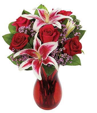 Red roses and pink lilies in a red glass vase