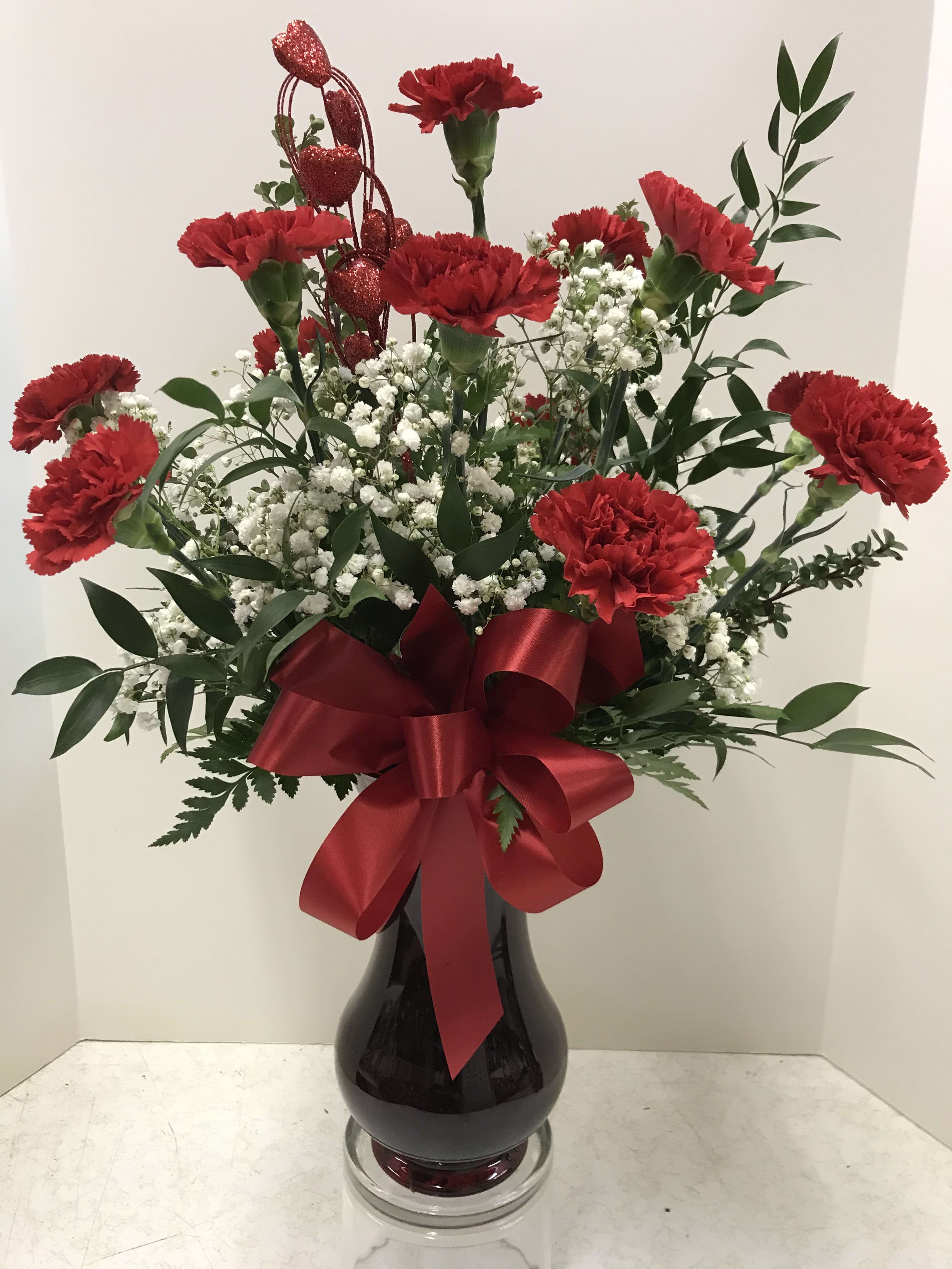 Red carnations in a black vase with a red ribbon bow