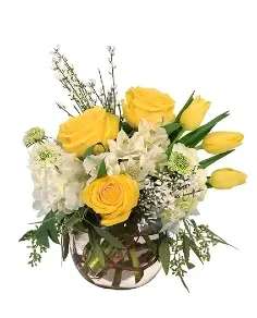 Yellow roses and white flowers arranged in a glass vase