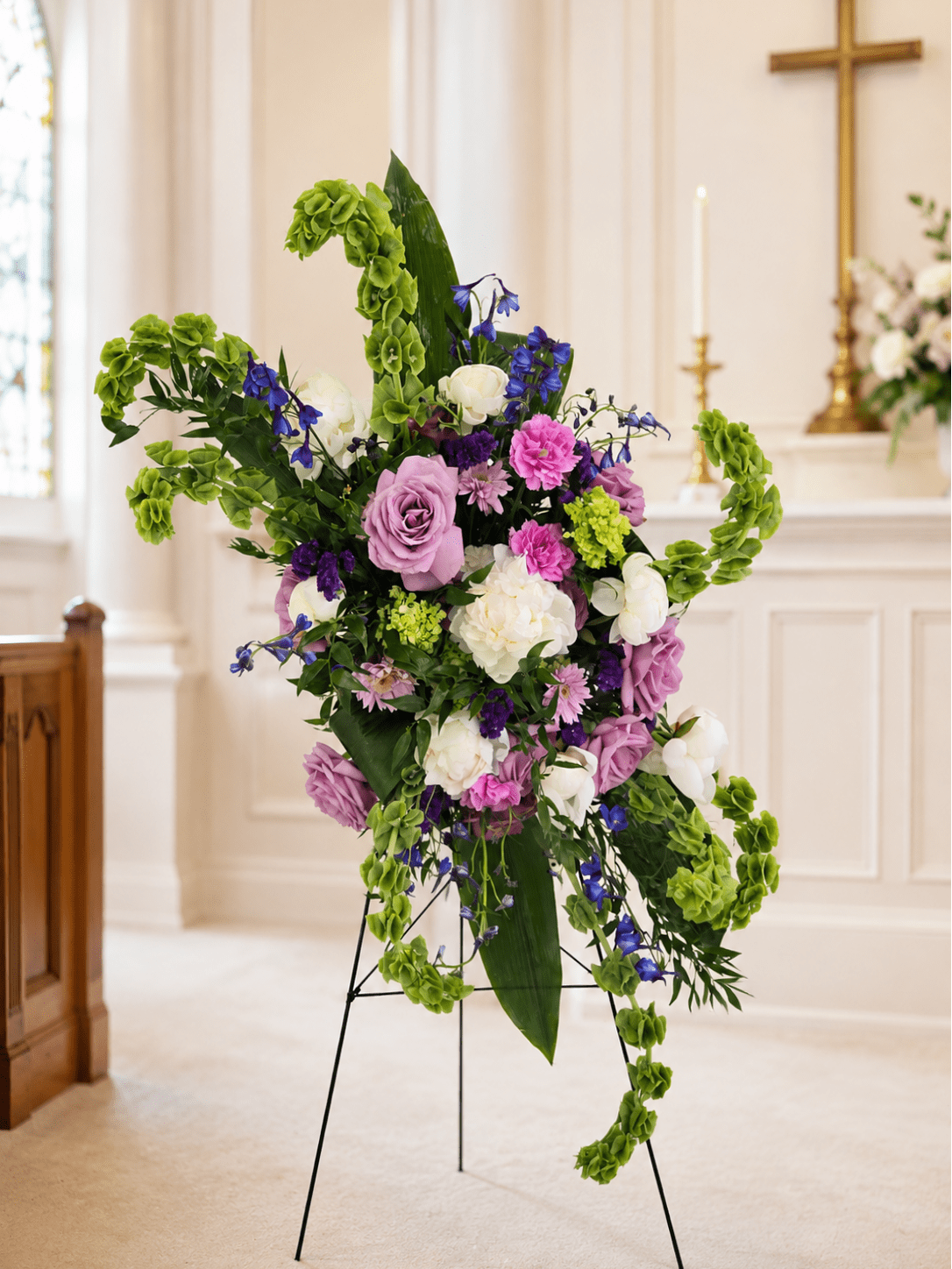 Tall floral spray with purple, white, and green blooms on a stand