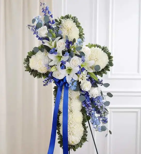 Standing Cross Spray: Blue &amp; White  - Celebrate a life of faith and devotion with our elegant sympathy arrangement. A bed of pristine white blooms is crafted into the shape of a cross by our caring florists. Flourishes of white and blue flowers cascade down the center. What a beautiful tribute to honor a loved one, while providing peace and comfort when it’s most needed.: including roses, lilies, delphinium mums, and more. 