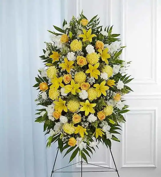 Yellow &amp; White Sympathy Standing Spray - A ray of hope can mean everything after the loss of a loved one. Both bright and abundant, our impressive standing spray arrangement, meticulously handcrafted by expert local florists with sunny yellow and rich white blooms, offers a grand gesture of peace, comfort and light during a difficult time.Standing spray arrangement with yellow roses and daisy poms; white yellow Asiatic lilies , gladiola, yellow football mums , carnations and monte casino; accented with soft, lush greenery