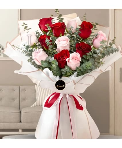 Bouquet of red and pale pink roses wrapped in white paper