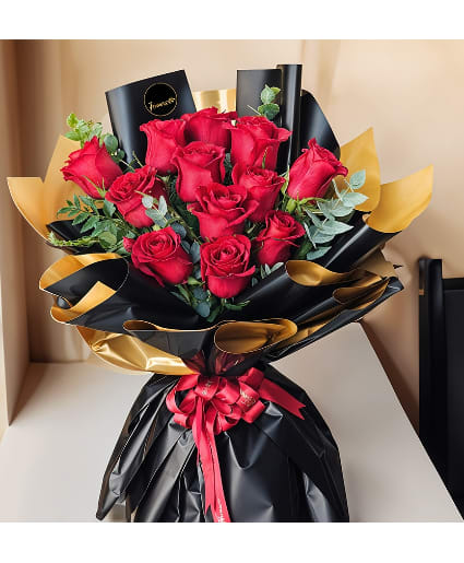 Bouquet of red roses wrapped in black and gold paper with a red ribbon