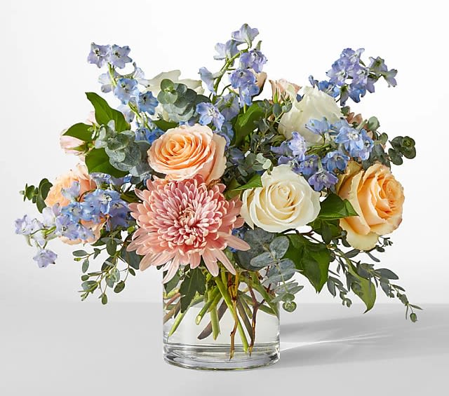 Bouquet of peach and white roses with pink chrysanthemum in a glass vase