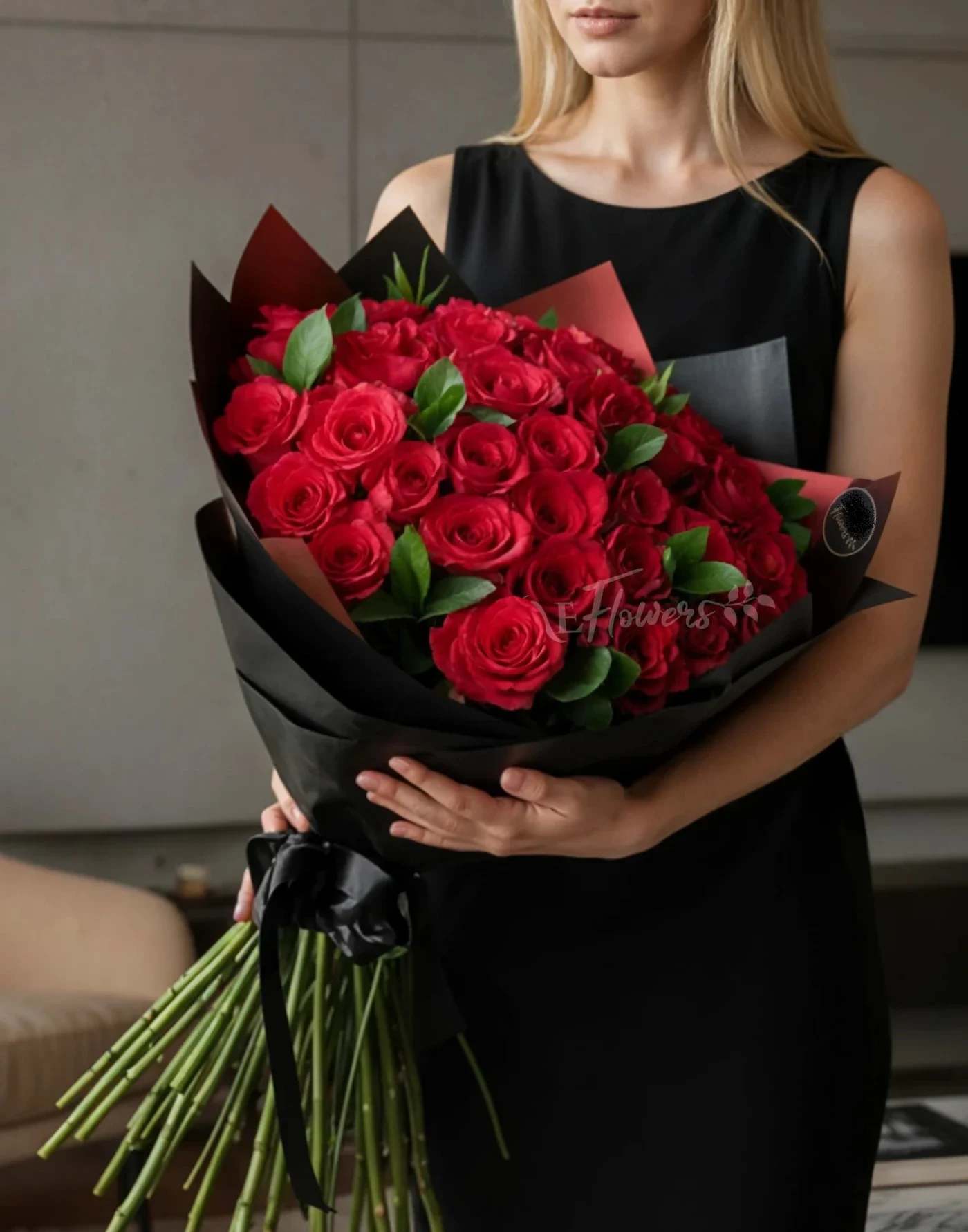 Woman holding a large bouquet of red roses wrapped in black paper