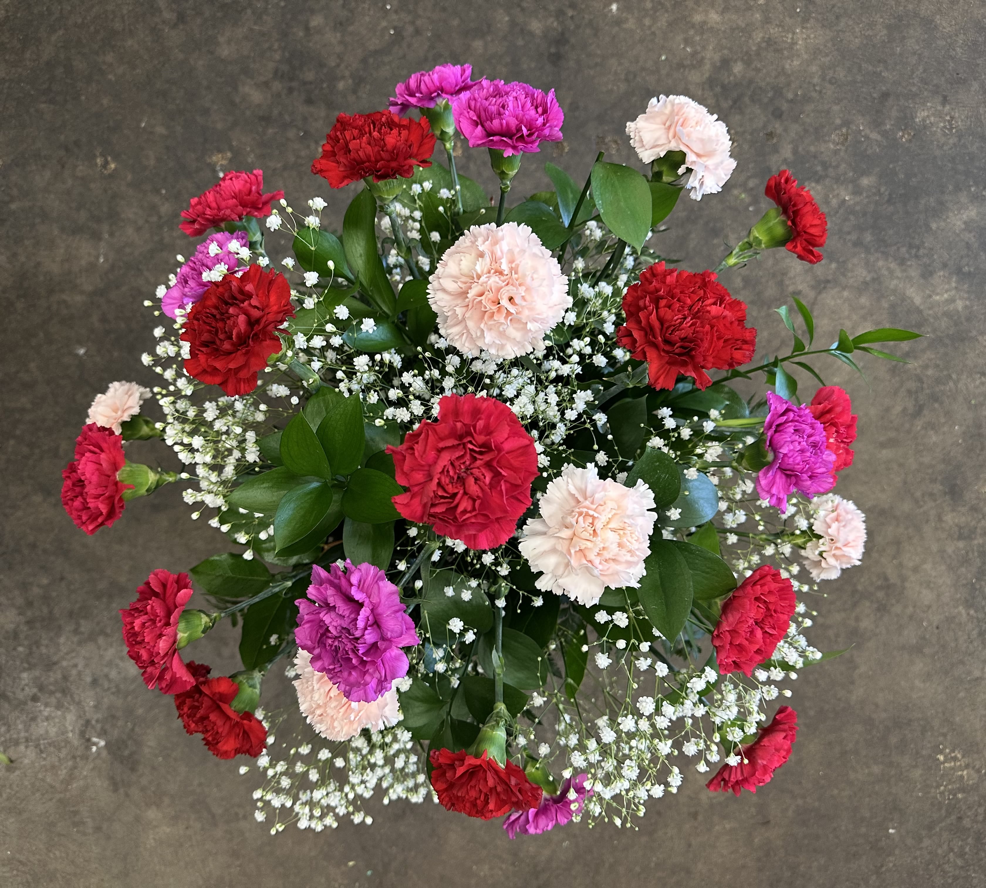 Blushing Keepsake - A full, airy arrangement of 25 premium carnations in assorted romantic colors thoughtfully spaced to let each bloom stand on its own. Accented with delicate baby’s breath, rich salal, and textured leatherleaf, this design feels abundant yet natural — not overly packed, just beautifully balanced.