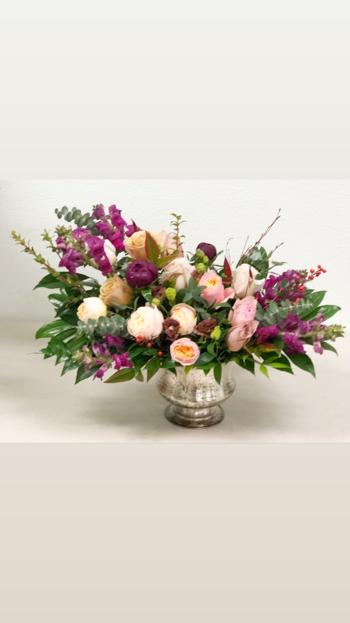 Mixed bouquet of pink, cream, and purple flowers in a silver vase
