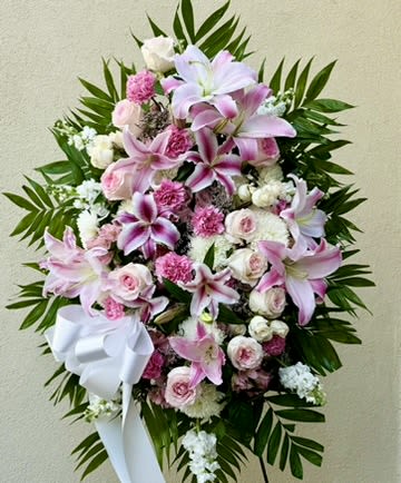 Pink and white floral standing spray with a white ribbon