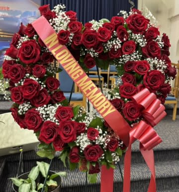 Heart-shaped wreath of red roses with white baby's breath and a memorial ribbon