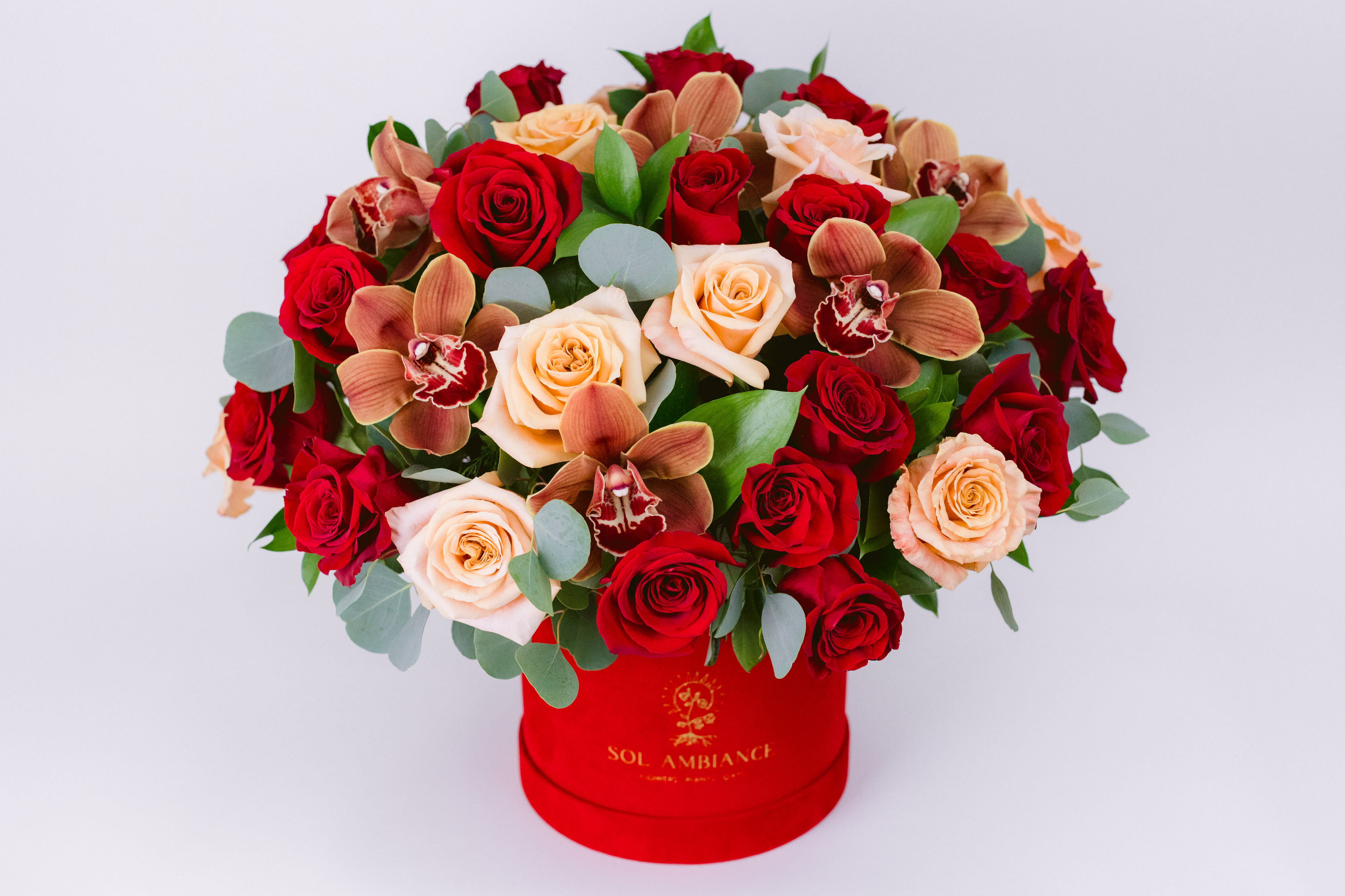 Red and peach roses with orchids in a red hat box