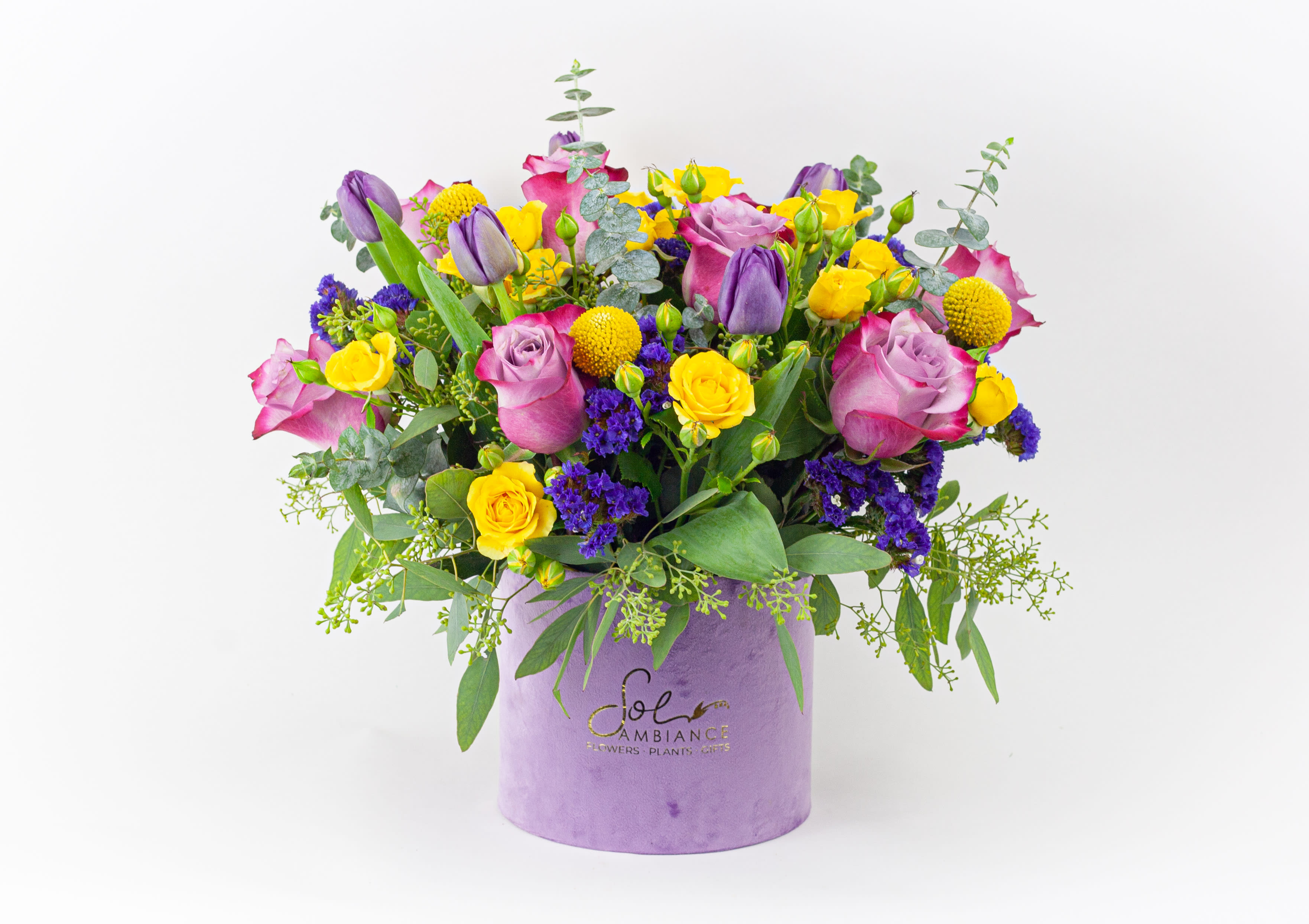 Mixed bouquet of pink, purple, and yellow flowers in a lavender box