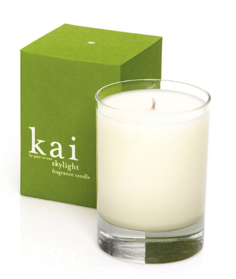 White candle in a clear glass tumbler beside a green box