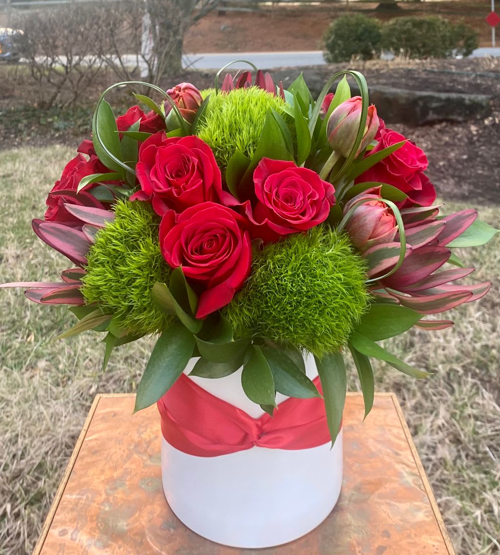 Red roses and green pom-pom flowers in a white hatbox with a red ribbon