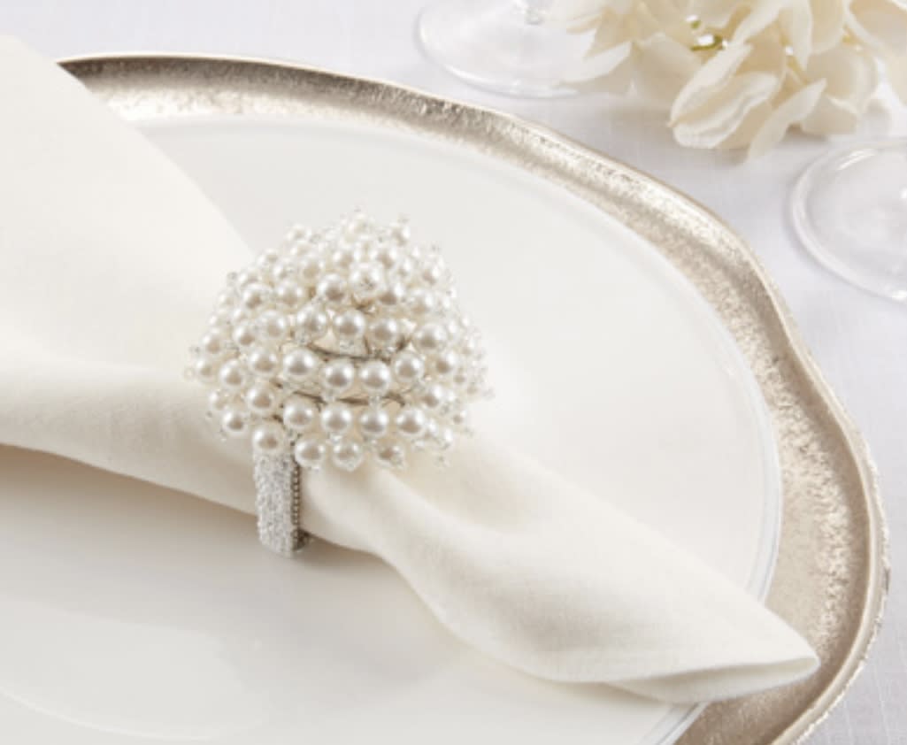 White napkin with a pearl napkin ring on a gold-rimmed plate