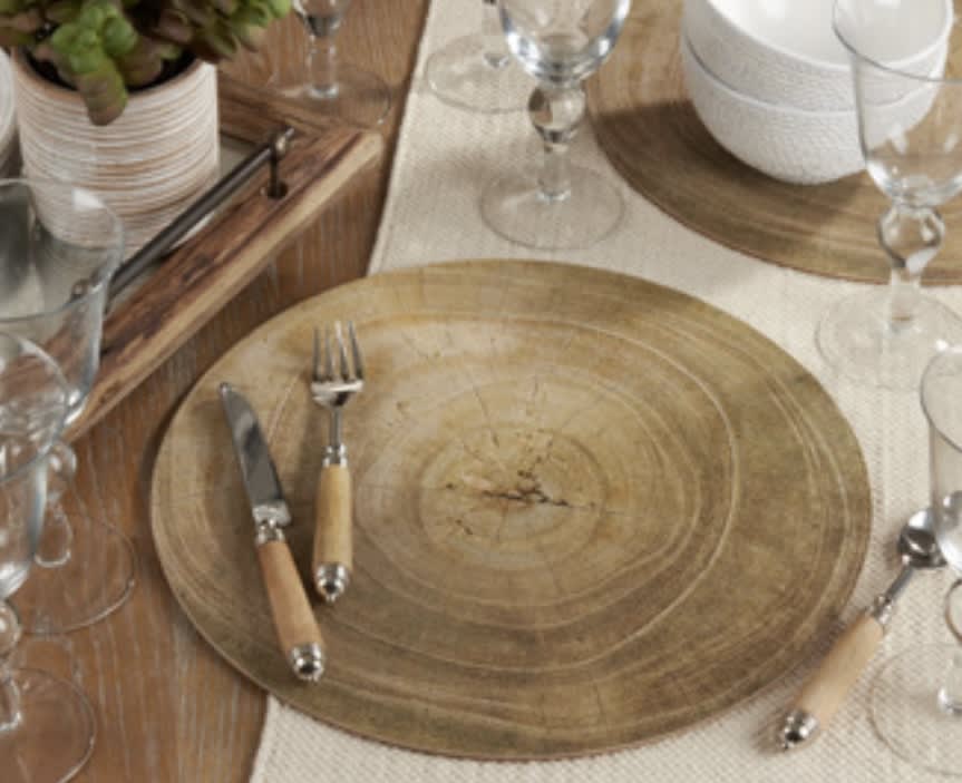 Wooden charger plates with silverware and glassware on a table setting