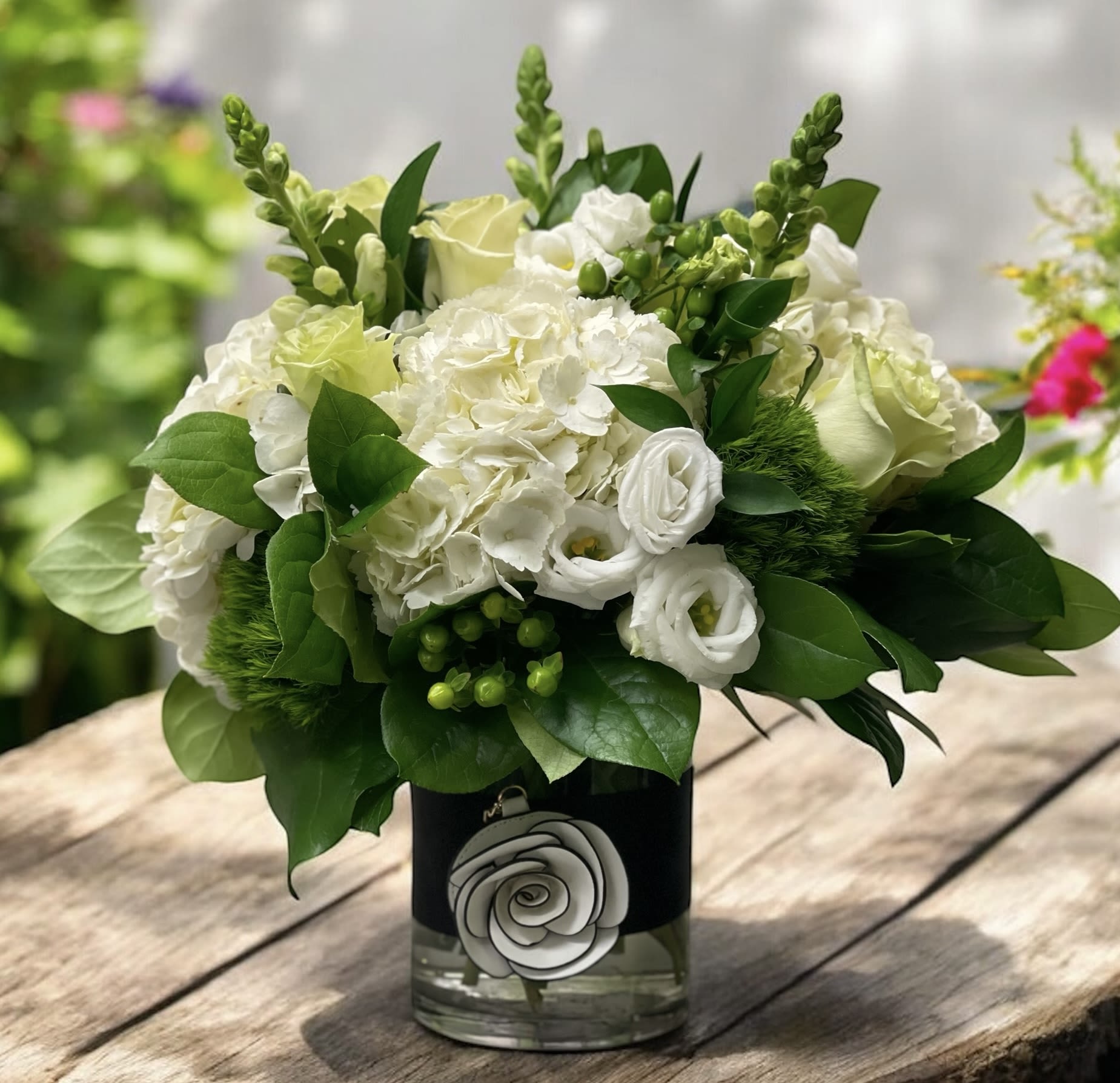 White floral arrangement in a glass vase with green foliage