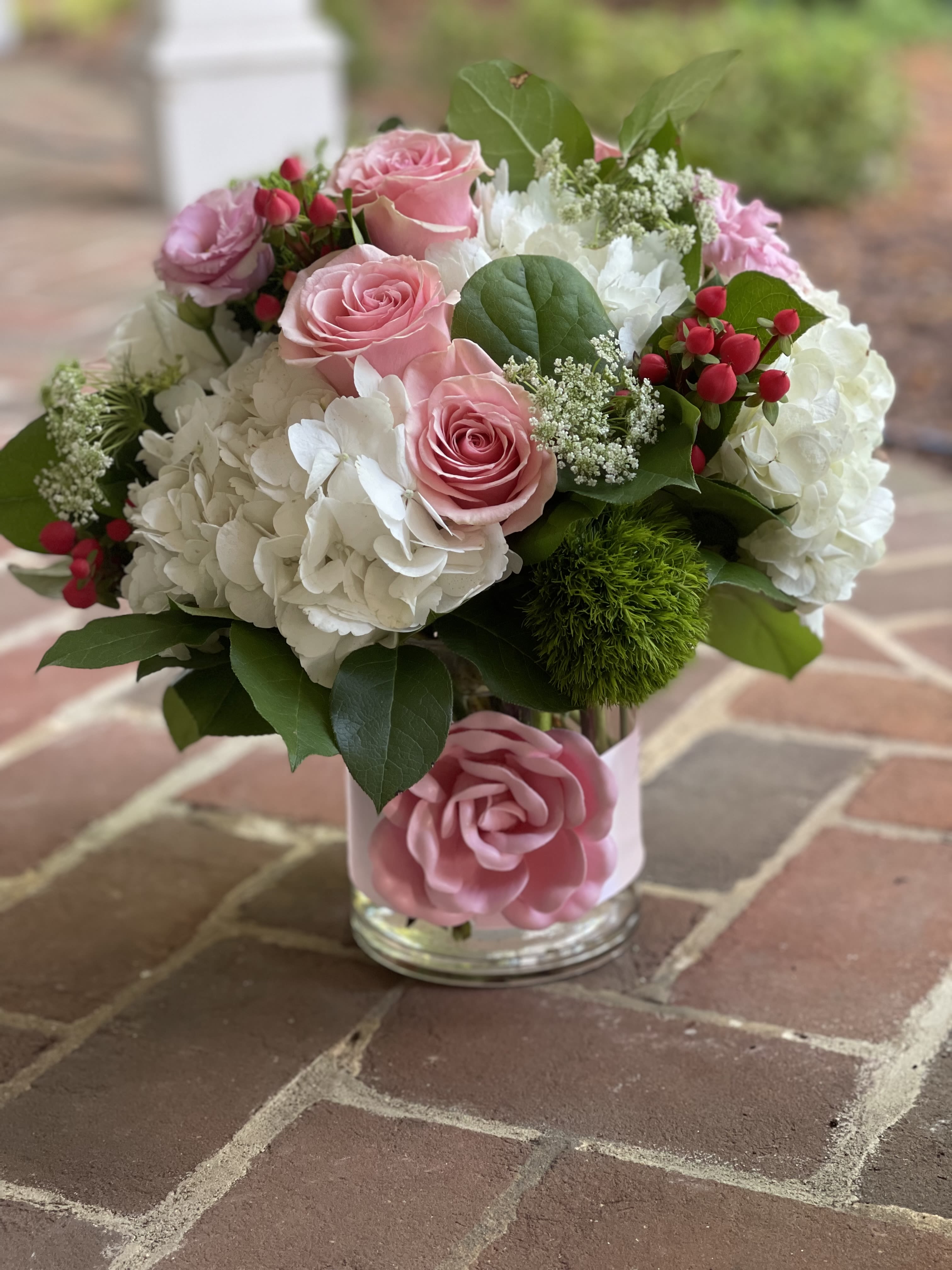 Pink roses and white hydrangeas in a glass vase with greenery