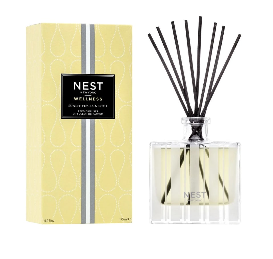 Yellow reed diffuser with black reeds beside its box