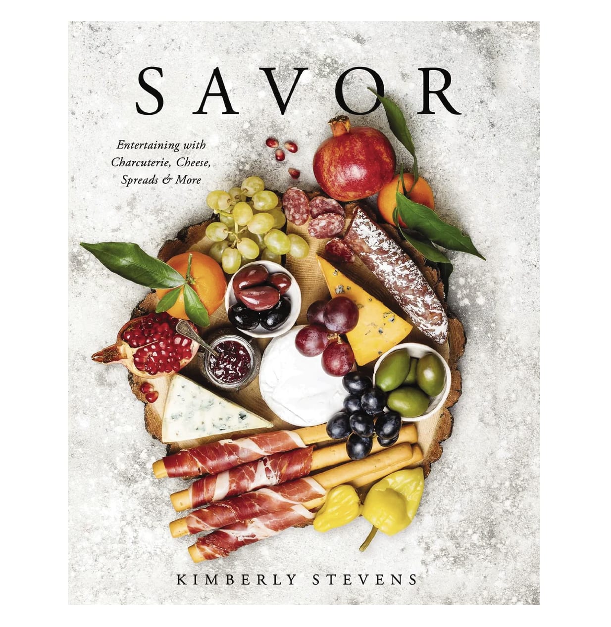 Charcuterie board with fruit, cheese, olives, and breadsticks on a book cover