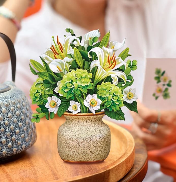 Arrangement of white lilies and green hydrangeas in a ceramic vase