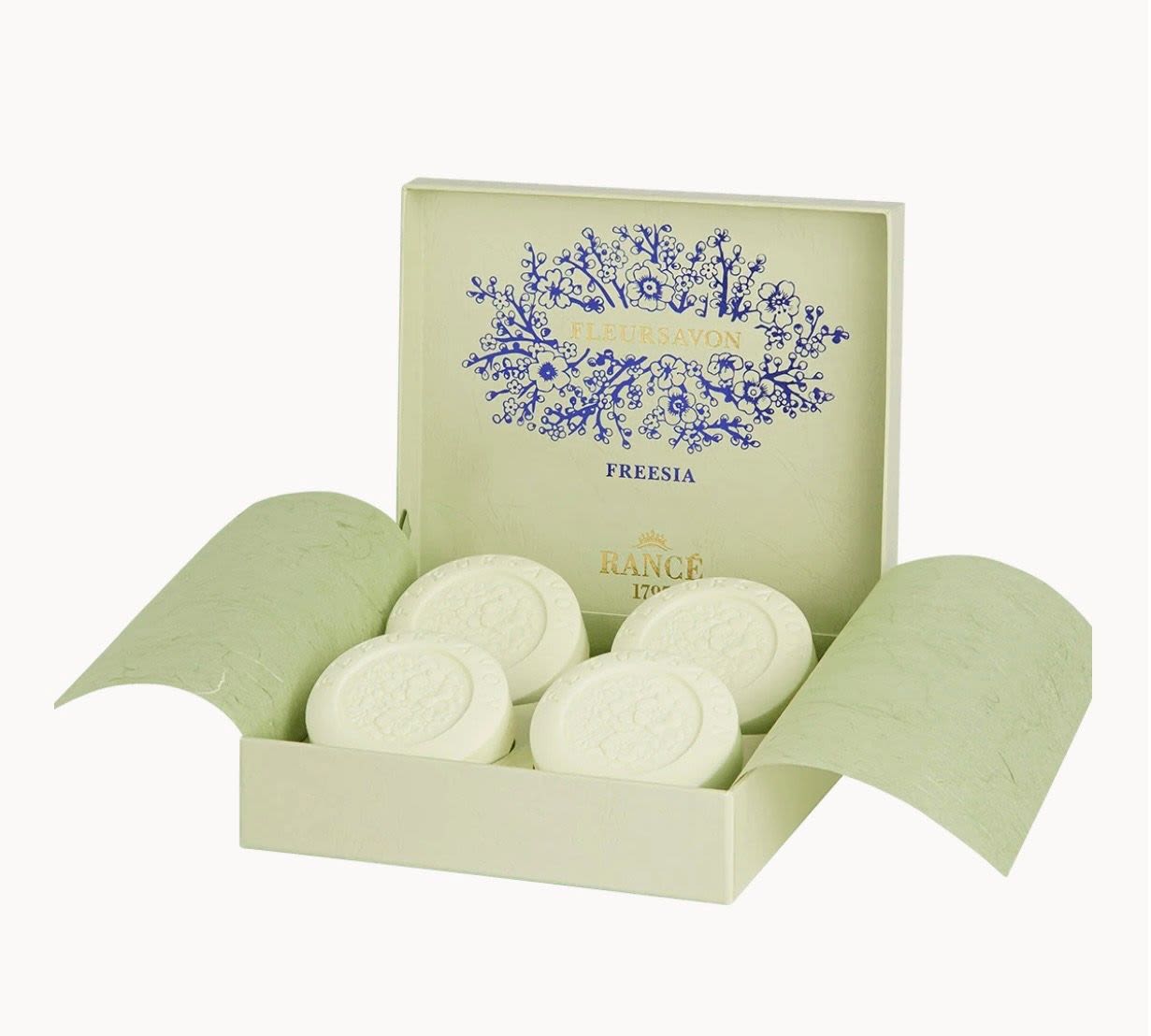 Open gift box with round white soaps and freesia branding