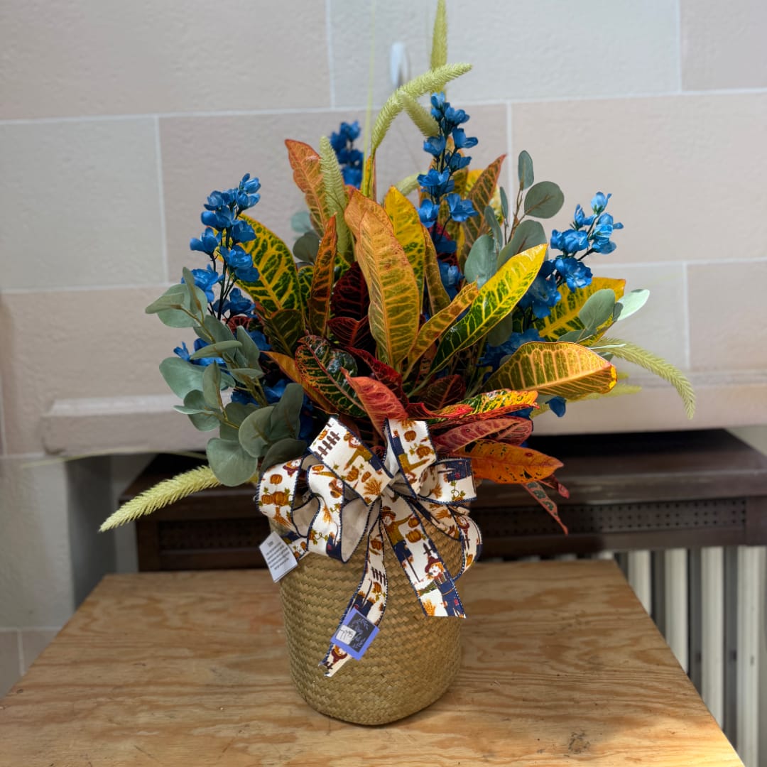 Colorful floral arrangement in a woven basket with a decorative ribbon