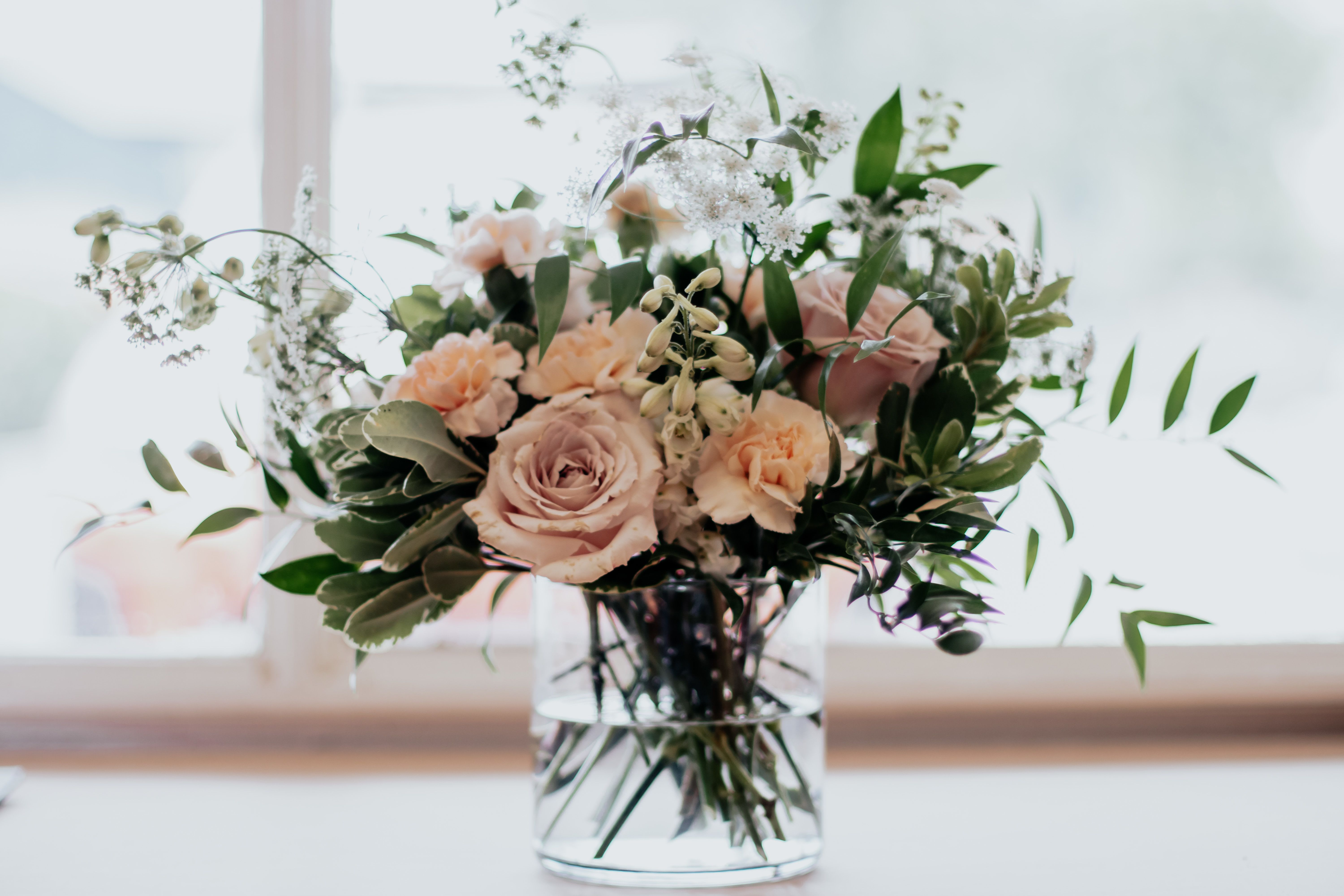 Blush roses and peach carnations in a clear glass vase
