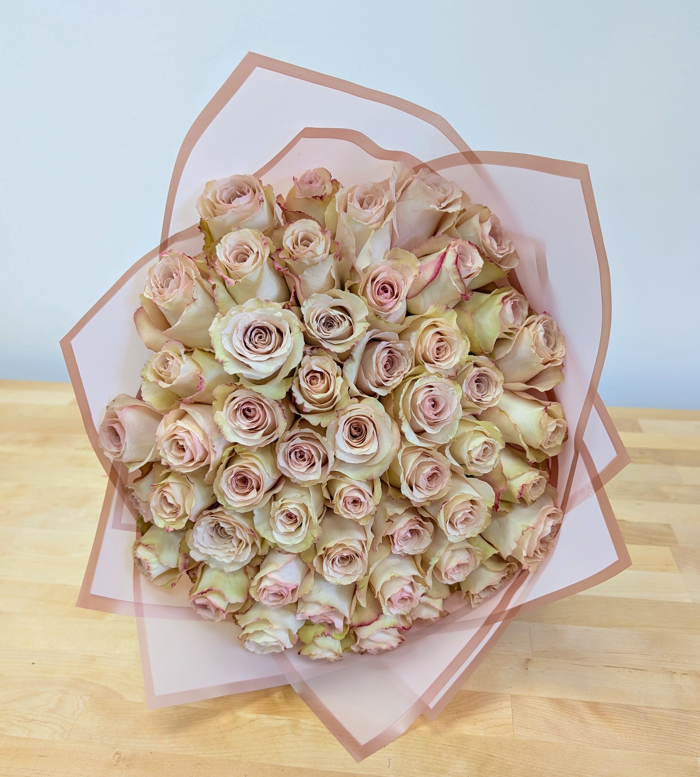Bouquet of pale pink roses wrapped in translucent pink paper