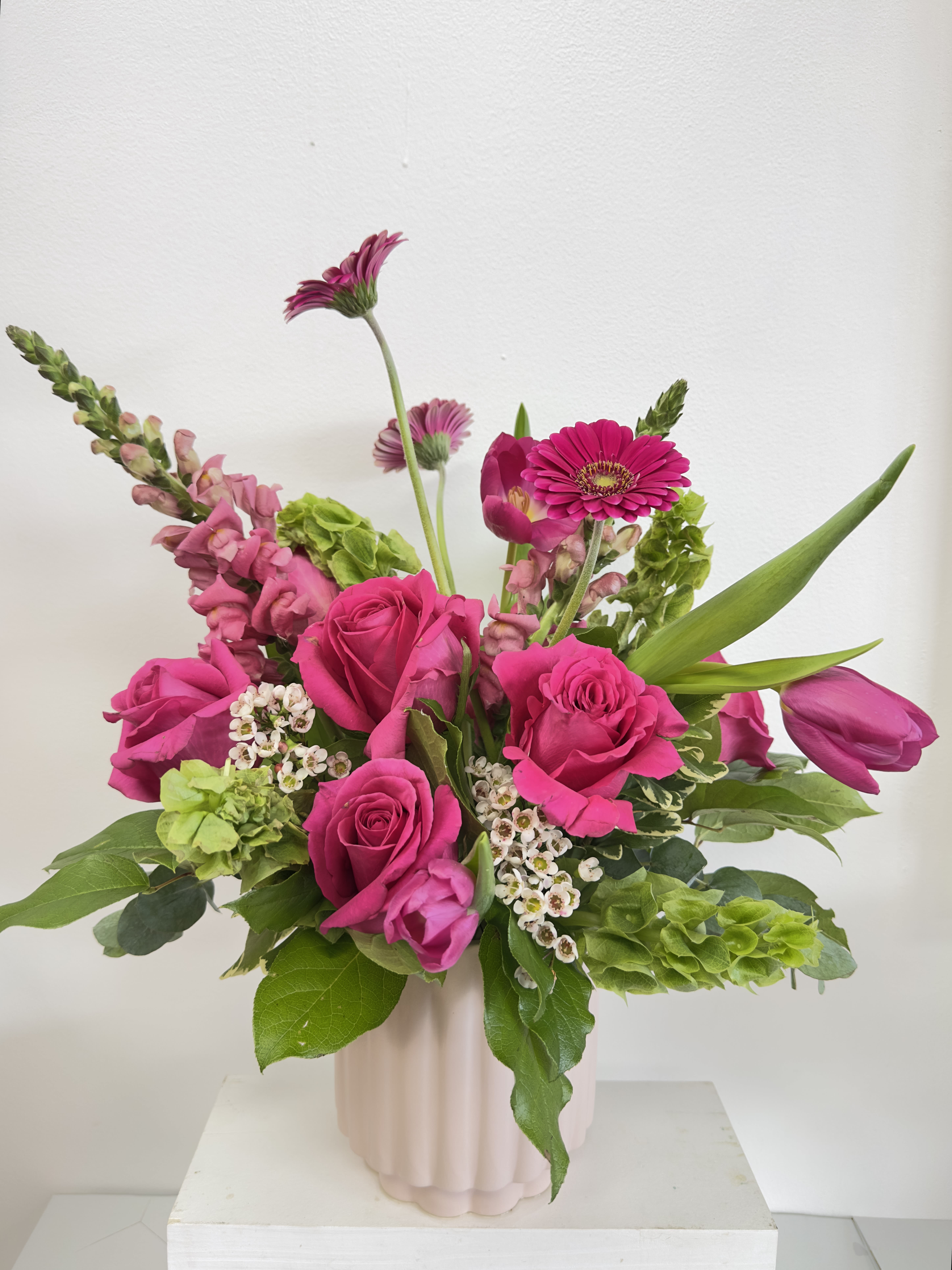 Pink roses and gerbera daisies in a pale vase