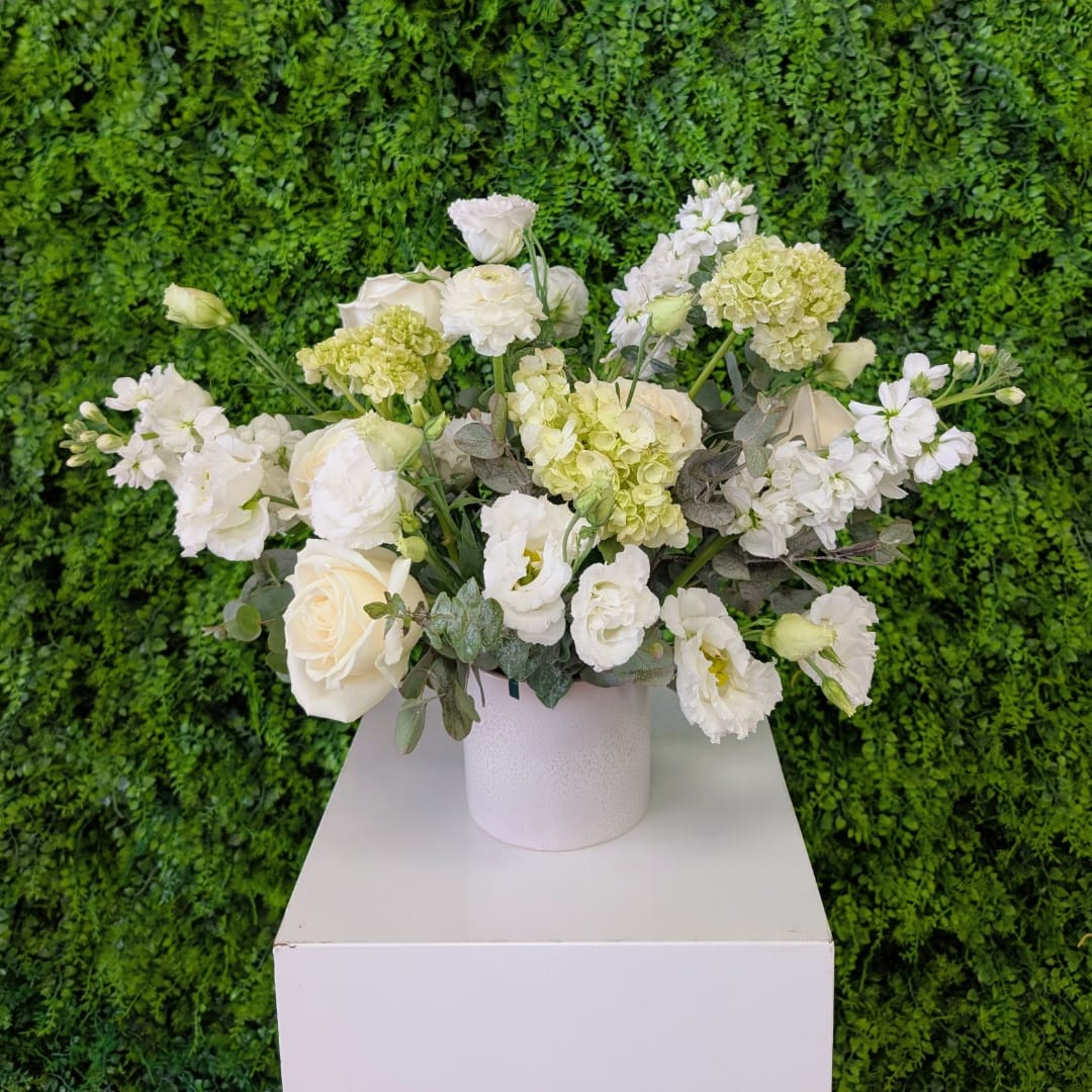White and pale green floral arrangement in a white vase