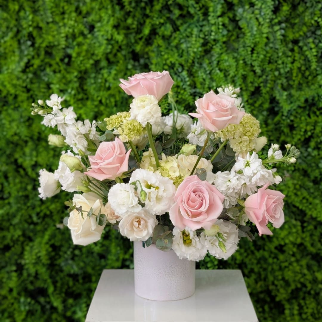 Pink and white roses arranged in a white vase