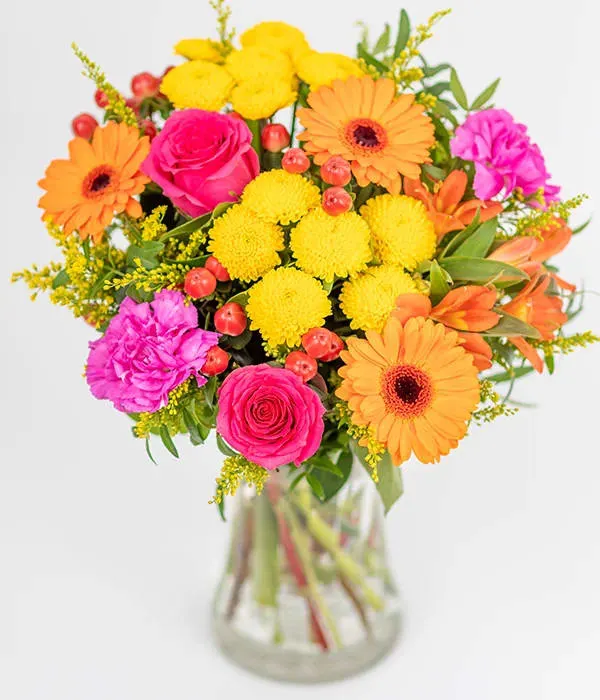 Tropical Sunset bouquet - This hand tied arrangement is bursting with vibrant blooms, including yellow, cerise, purple, and orange stems, decorated with seasonal foliage.