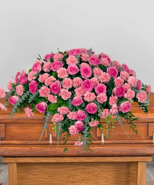 Pink roses and carnations arranged on a wooden casket