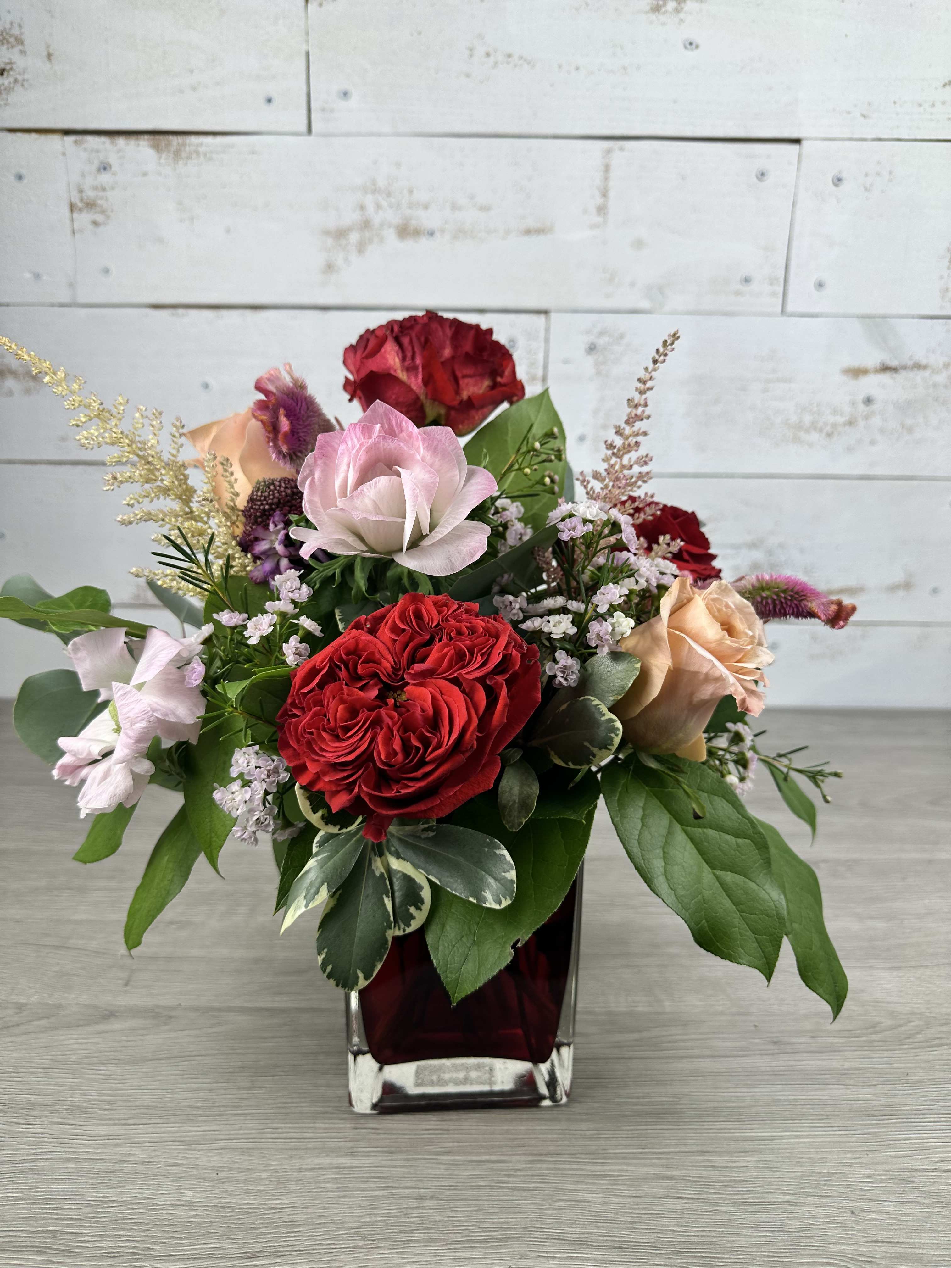 Mixed rose arrangement in a square glass vase